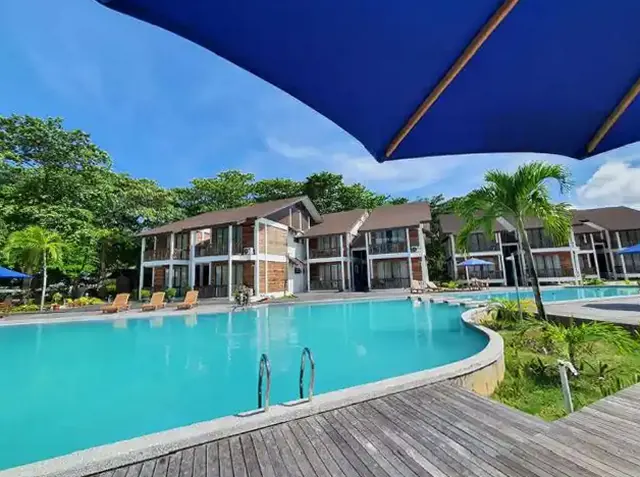Curved swimming pool and wooden deck in front of the two-storey villa buildings at Borneo Divers Mabul Resort