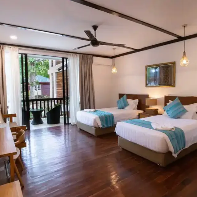 Villa room with two beds, wooden floor and a balcony door at Borneo Divers Mabul Resort