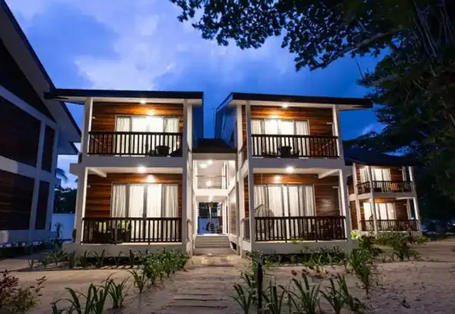 Two-storey villa buildings with lit balconies at dusk, Borneo Divers Mabul Resort