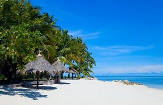Shaded beach shelters beside the sea at Sipadan-Mabul Resort